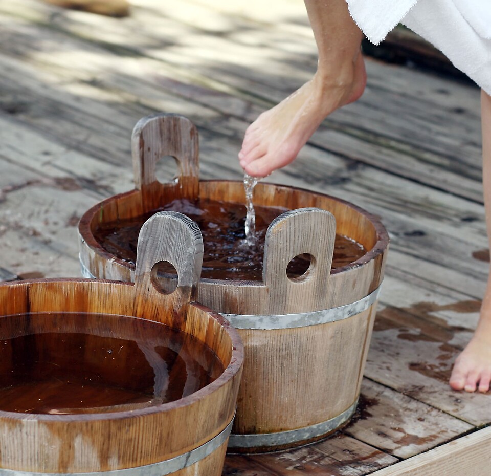 Gesund durch Wasser – Kneippen im Wellnesshotel Eschenhof in Bad Kleinkirchheim Kneipp-Anwendung im Holzschaff im Wellnessbereich des Naturhotel Eschenhof in Bad Kleinkirchheim – zwei Beine sichtbar